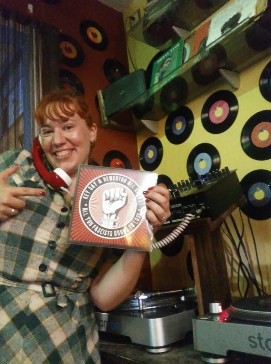 Una DJ muestra un single de vinilo junto a sus platos