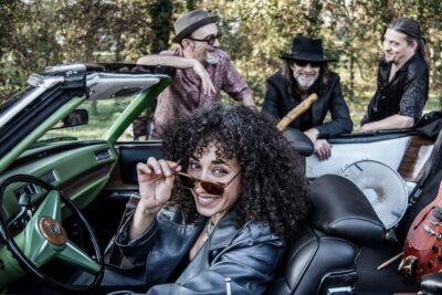 La cantante de Sweet Marta & The Blues Shakers al volante de un descapotable verde con sus músicos detrás
