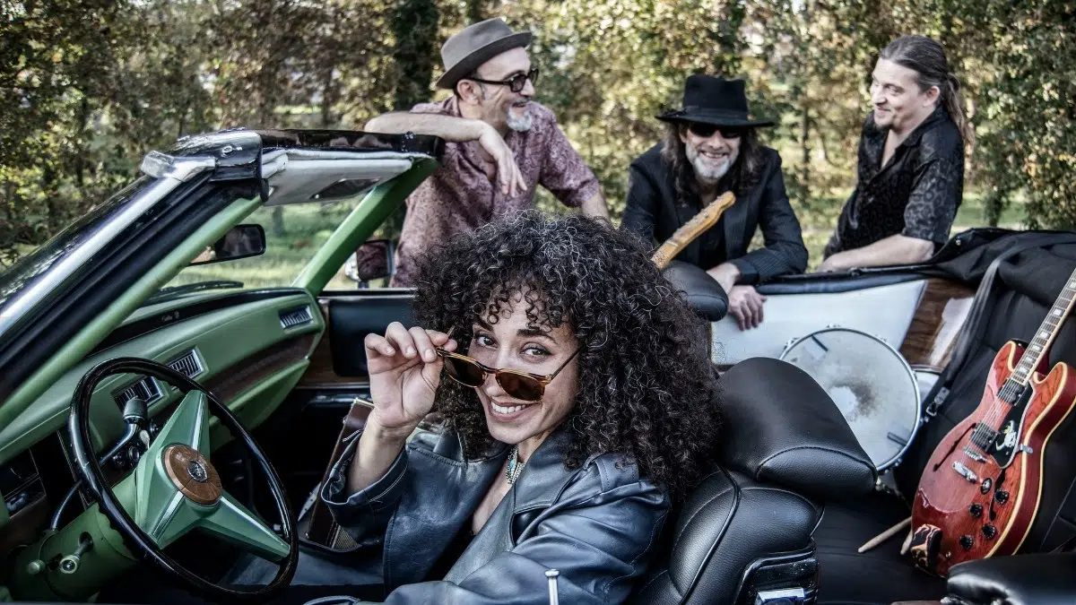 La cantante de Sweet Marta & The Blues Shakers al volante de un descapotable verde con sus músicos detrás