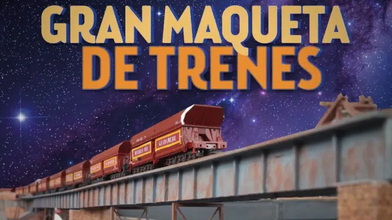 Tren de tolvas a escala cruzando un puente metálico bajo un cielo estrellado, con el rótulo Gran Maqueta de Trenes